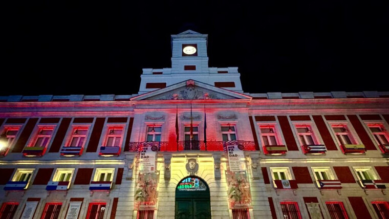 La Real Casa de Correos se ilumina en rojo y gualda para celebrar la Fiesta Nacional en Madrid