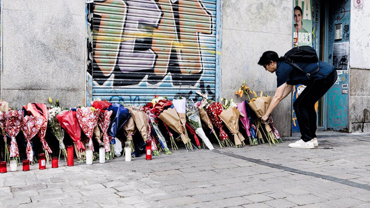 Una mujer deposita un ramo de flores en la tienda de uniformes de trabajo 'Vistebien', donde el pasado lunes, 3 de julio, apuñalaron a Conchi, en Tirso de Molina